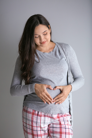 Beautiful pregnant woman on grey backgroundの写真素材