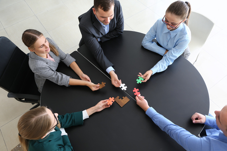 Business team assembling puzzle on dark tableの写真素材