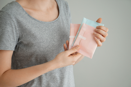 Woman holding menstrual pads on grey backgroundの写真素材