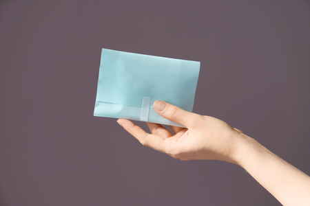 Woman holding menstrual pad on color backgroundの写真素材