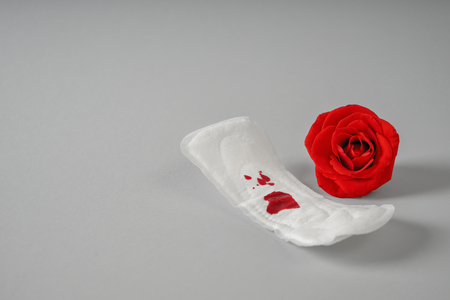 Menstrual pad with red stain and rose on grey backgroundの写真素材