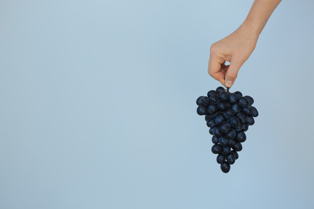 Woman holding ripe sweet grapes on color backgroundの写真素材