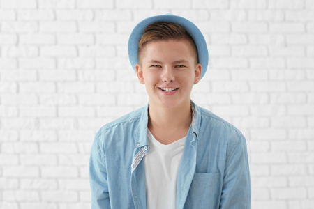 Portrait of handsome smiling young man against white brick wallの写真素材