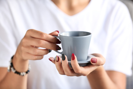 Woman with stylish beautiful manicure drinking coffee, closeupの写真素材