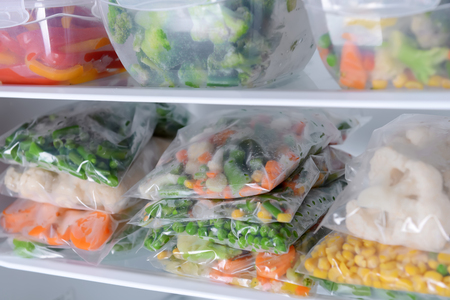Plastic bags and containers with frozen vegetables in refrigeratorの写真素材