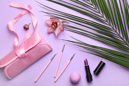 Decorative cosmetics with tropical leaves and flower on color backgroundの写真素材