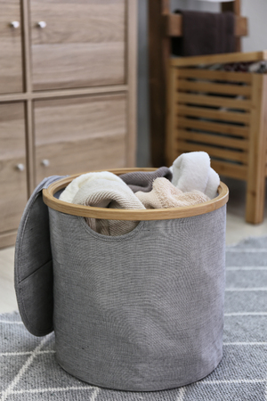Laundry basket with dirty towels on floor in roomの写真素材