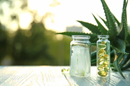 Bottles with peeled aloe vera and pills on table outdoorsの写真素材