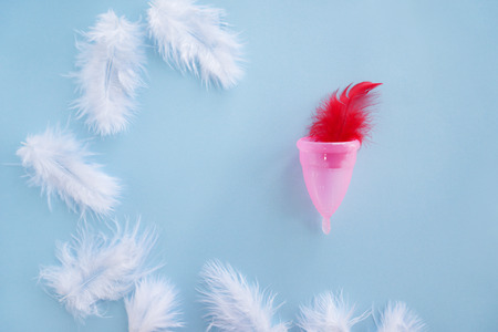 Menstrual cup with feathers on color backgroundの写真素材