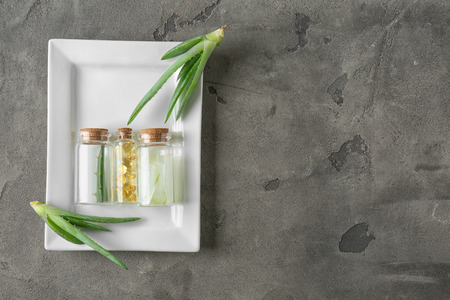 Bottles with pills, peeled and fresh aloe vera on plateの写真素材