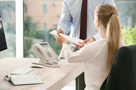 Beautiful female secretary working with colleague in officeの写真素材