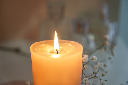 Beautiful burning candle with flowers on shelf, closeupの写真素材