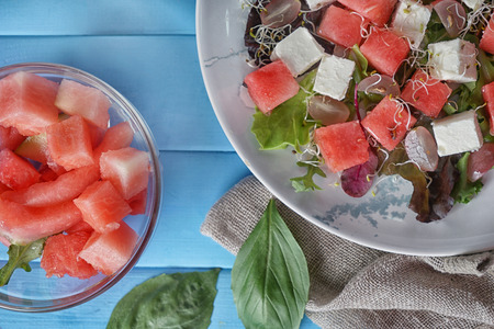 Plate with delicious watermelon salad on color wooden table, top viewの写真素材