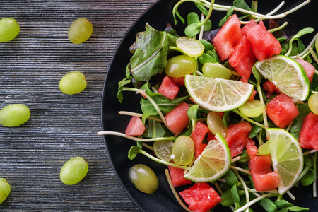 Plate with delicious watermelon salad on wooden tableの写真素材