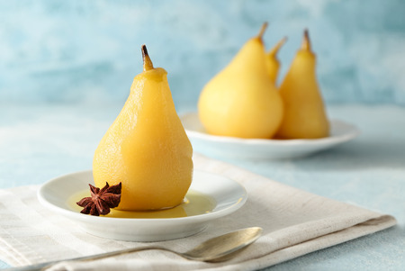 Plate with delicious poached pear in wine on color tableの写真素材
