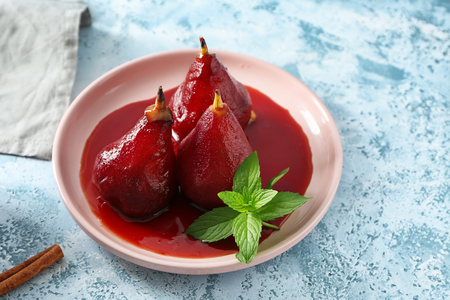 Plate with delicious poached pears in red wine on color tableの写真素材