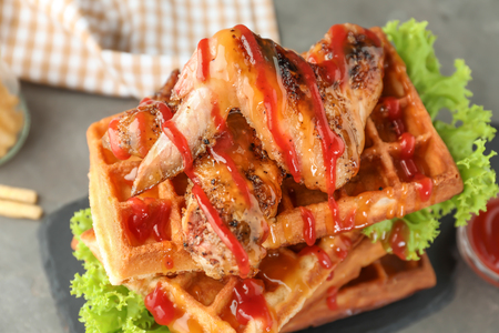 Delicious waffles with chicken wings and sauce on slate plate, closeupの写真素材