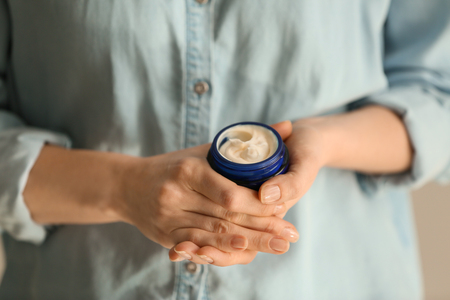 Woman holding jar of body cream, closeupの写真素材