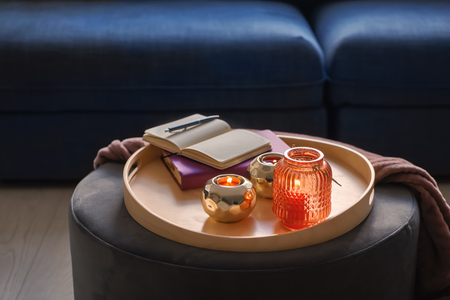 Composition with burning candles in decorative holders and notebooks on tray indoorsの写真素材