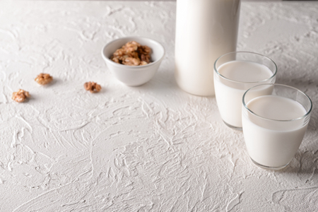 Glasses and bottle of tasty milk on white tableの写真素材