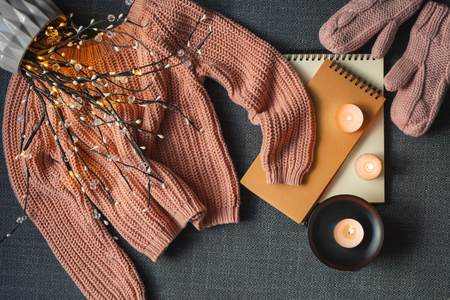 Composition with warm sweater and burning candles on dark background