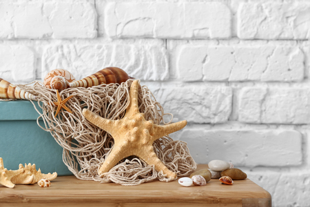 Starfish, seashells and pebbles as decorations on table near white brick wallの写真素材