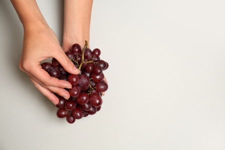 Ripe tasty grapes in female hands on white backgroundの写真素材