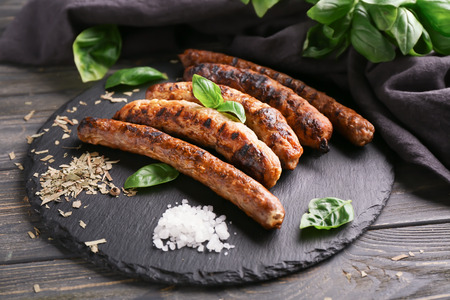 Delicious grilled sausages with spices on slate plateの写真素材