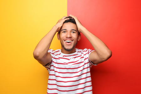 Portrait of happy African-American man on color backgroundの写真素材