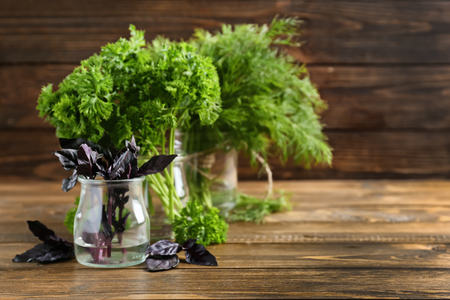 Jars with fresh aromatic herbs on wooden tableの写真素材
