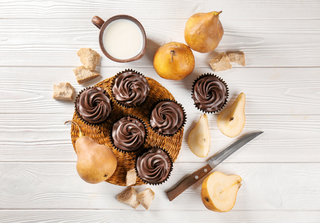 Composition with chocolate cupcakes, cup of milk and pears on wooden tableの写真素材