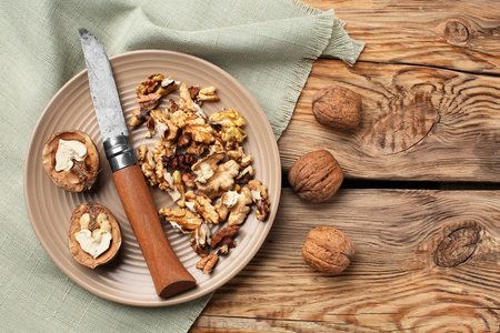 Plate with tasty walnuts and knife on wooden tableの写真素材