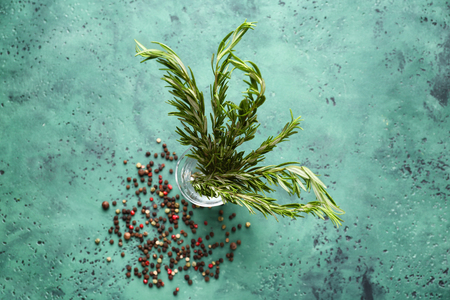 Glass with fresh aromatic rosemary and spices on color tableの写真素材