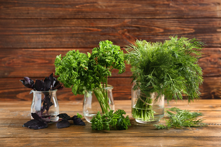 Jars with fresh aromatic herbs on wooden tableの写真素材