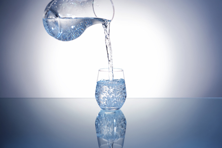 Pouring of water in glass on table