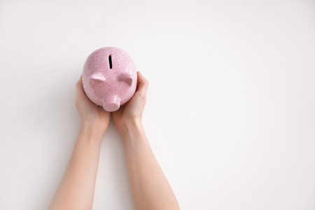 Female's hands holding piggy bank on white background, top viewの写真素材