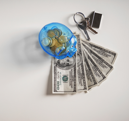 Piggy bank, money and keys on white background. Concept of saving money for buying new houseの写真素材