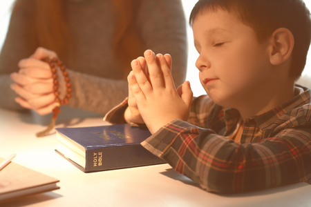 Little boy and his mother praying at homeの写真素材