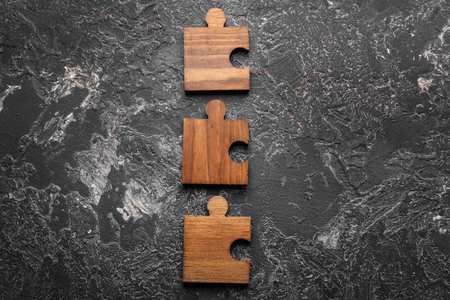 Pieces of wooden puzzle on grey textured background