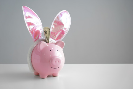 Piggy bank with bunny ears on table. Concept of saving money for holidayの写真素材