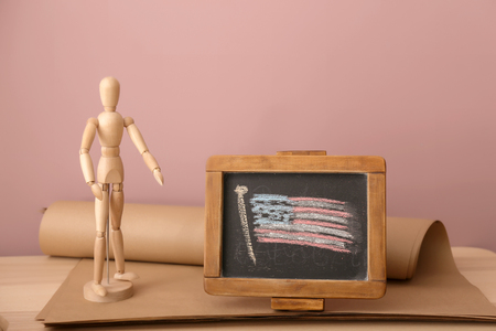Chalkboard with drawing of American national flag and small mannequin on wooden tableの写真素材
