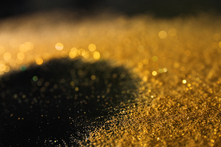 Golden glitters on dark background, closeupの写真素材