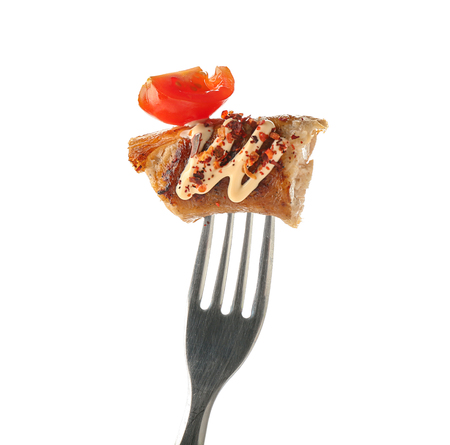 Fork with piece of delicious grilled sausage, sauce and tomato on white backgroundの写真素材