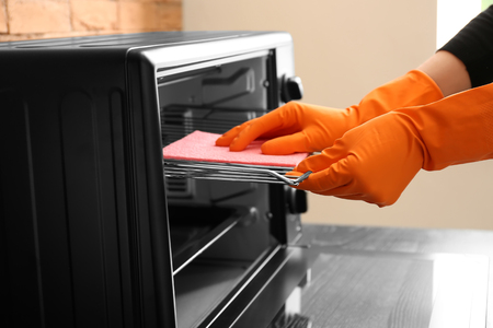 Woman cleaning electric oven with rag, closeupの写真素材