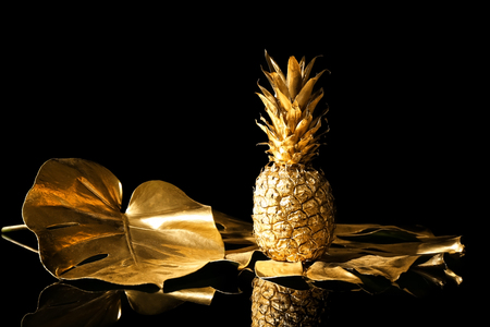 Golden tropical leaves with pineapple on black backgroundの写真素材