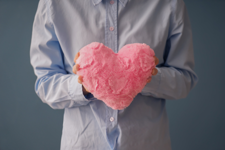 Woman holding fabric heart on grey backgroundの写真素材