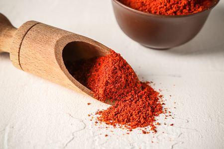 Wooden scoop with paprika powder on tableの写真素材
