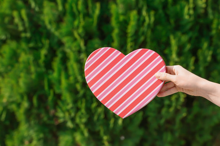 Woman holding heart shaped gift box on blurred backgroundの写真素材