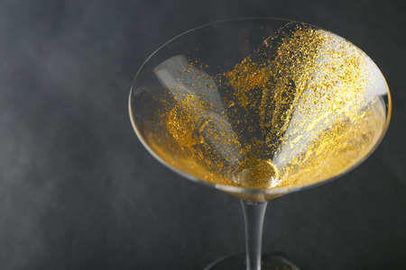 Glass with golden glitter on dark backgroundの写真素材
