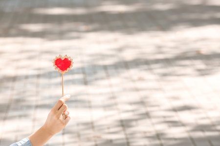 Woman holding heart shaped lollipop outdoorsの写真素材